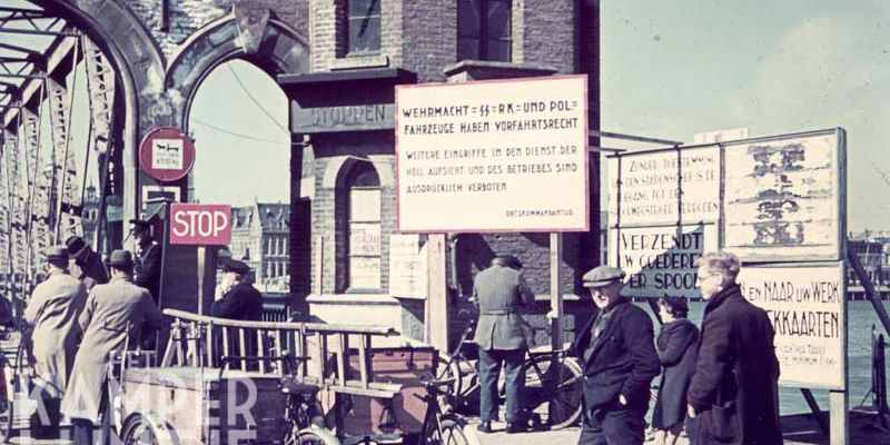 3c. Kampen 1940 – 1945, controle bij IJsselbrug. Op het bord: ‘Zonder toestemming van een stationschef is de toegang tot de spoorsteiger verboden’  en ‘Verzendt uw goederen per spoor’ en ‘Van en naar uw werk weekkaarten’